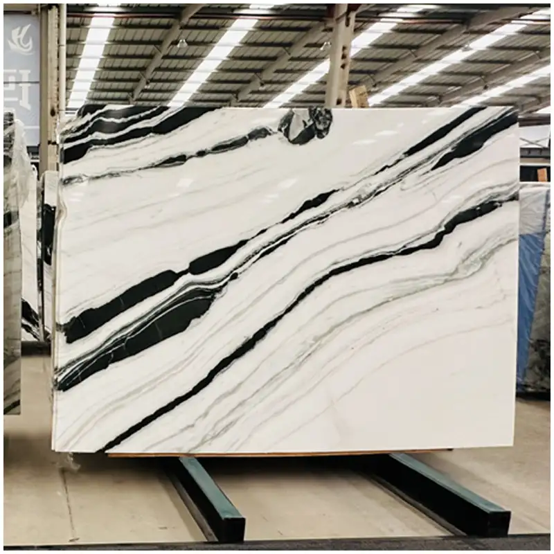 Chinese-Panda-Marble Esta Stone Chinese Panda White Marble slabs stacked in warehouse, showcasing continuous black and white vein patterns.