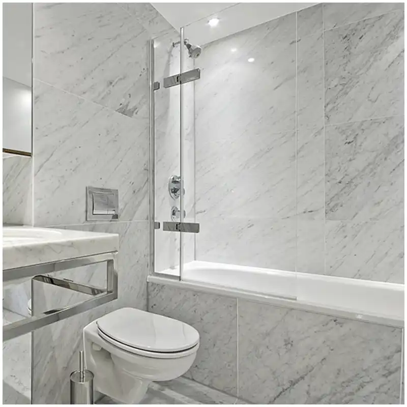 Carrara marble shower floor mosaic arranged around a drain for slope inspection