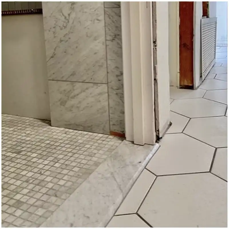 Carrara marble threshold section showing slope edge and waterproofing interfaces Carrara marble threshold section showing slope edge and waterproofing interfaces
